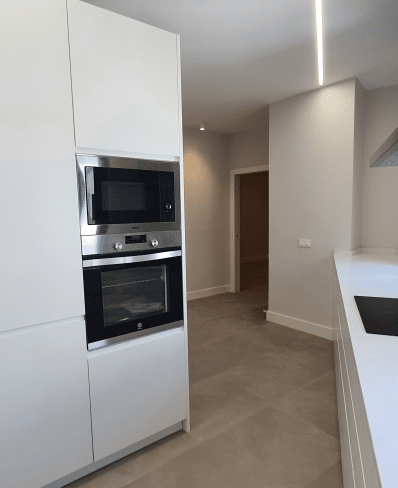 Imagen de una cocina moderna reformada por MAM Experience Building, con electrodomésticos integrados, diseño minimalista y acabados en tonos claros que aportan luminosidad al espacio.</p>
<p>