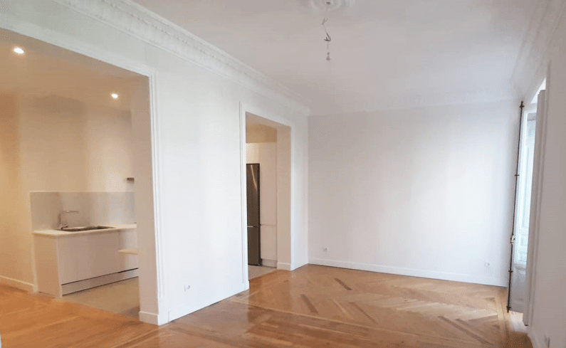 Imagen de un espacio reformado por MAM Experience Building, mostrando un diseño abierto y moderno con acabados en tonos claros, suelos de madera y detalles arquitectónicos que aportan elegancia y amplitud al área.