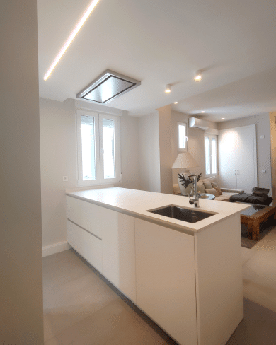 Imagen de una cocina reformada por MAM Experience Building, con una isla central con fregadero, iluminación moderna y un diseño abierto que se integra con la sala de estar.