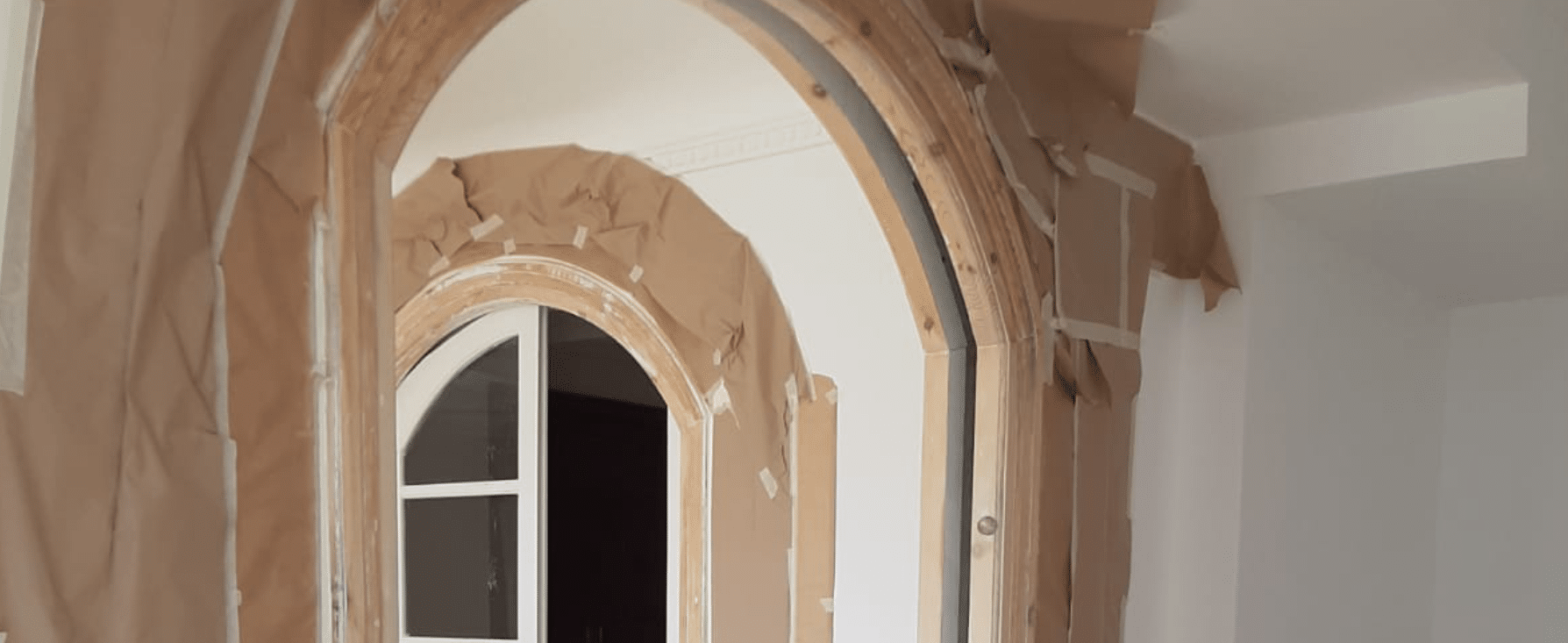Imagen del proceso de restauración de arcos interiores realizado por MAM Experience Building, mostrando el cuidado en la renovación de detalles arquitectónicos clásicos con enmascarado para proteger las superficies durante la obra