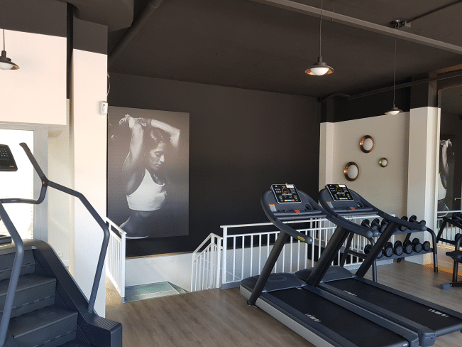 Interior de un gimnasio en Madrid reformado por MAM Experience Building, mostrando un diseño moderno con equipo de última generación, áreas de cardio, y una decoración elegante y funcional.